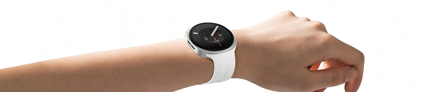 Galaxy Watch9 na cor Creme com Pulseira Sport na cor Branco, usado no pulso de uma pessoa, levemente angulado para a direita, destacando o visual fino e suave do relógio com o icônico design almofadado, além da Pulseira Sport fina e flexível para um encaixe confortável ao longo do dia, com espaço mínimo graças a Tecnologia de Encaixe.