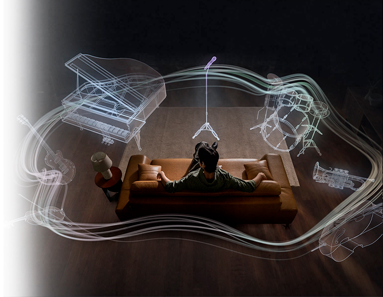 A imagem mostra um homem sentado no sofá enquanto instrumentos surgem ao seu redor (microfone, bateria, trompete, violoncelo, violino, guitarra e piano de cauda) ilustrando o sistema Áudio 360 do Galaxy Buds4.