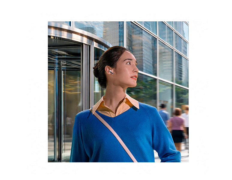 A imagem mostra uma mulher usando um Galaxy Buds4 branco, olhando para a direita, em frente a um edifício.