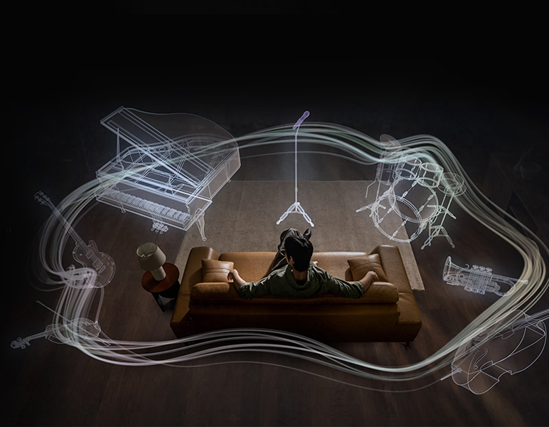 A imagem mostra um homem sentado no sofá enquanto instrumentos surgem ao seu redor (microfone, bateria, trompete, violoncelo, violino, guitarra e piano de cauda) ilustrando o sistema Áudio 360 do Galaxy Buds4 Pro