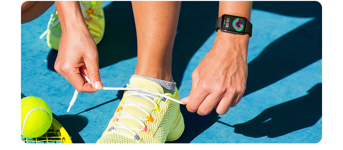 Vemos duas mãos amarrando cadarços de um tênis com uma delas usando o Galaxy Fit3 com o recurso de rastreamento de atividade diária em seu visor. 
