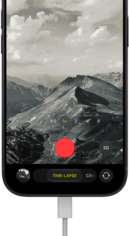Parte da frente do iPhone 18 Pro mostrando uma paisagem montanhosa, com a sobreposição do modo da câmera no modo time-lapse, com o cabo de energia conectado à porta para recarga